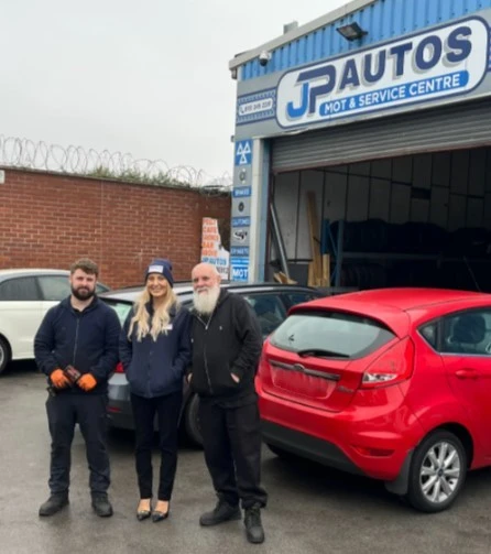 BookMyGarage employee stood between J P Autos staff outside front of garage